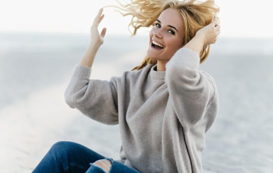 Good-humoured woman having fun at sea coast in autumn weekend. Outdoor shot of caucasian funny girl laughing on nature background