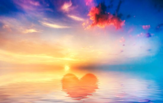 Hearth shape in calm ocean at sunset. Beautiful sky, clouds and colors
